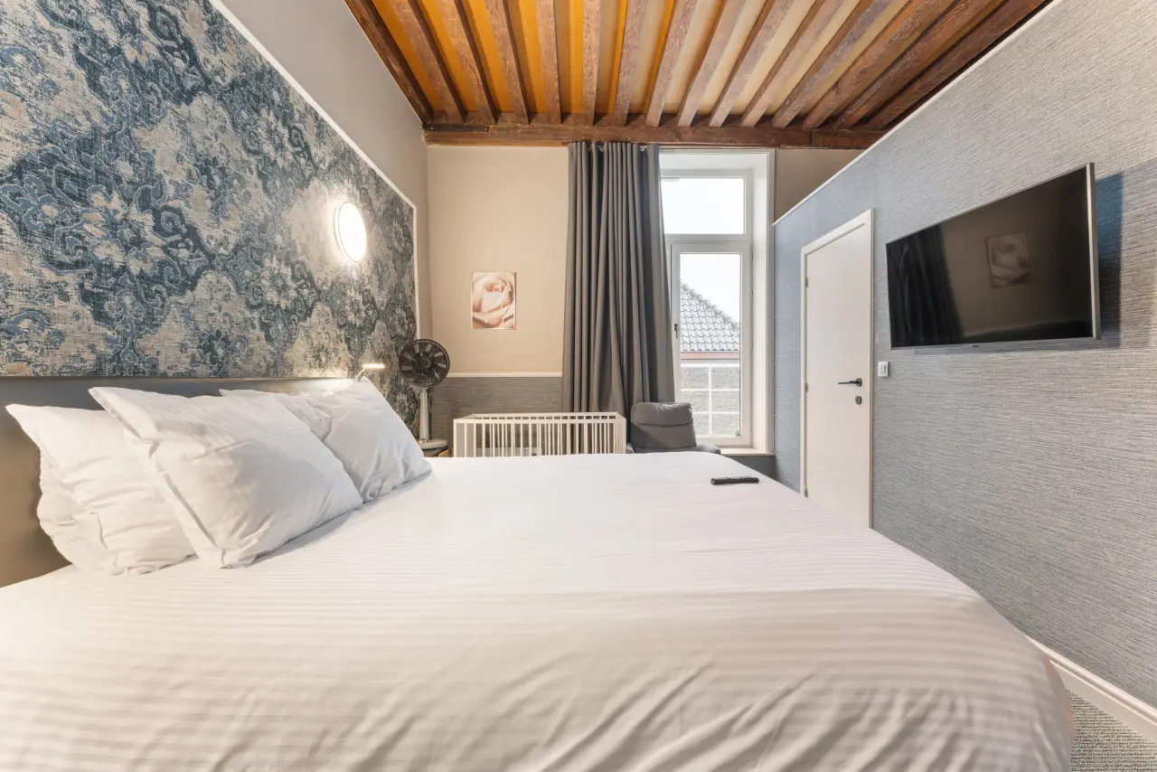 The wooden-beamed ceiling above the bed in a triple room at Hotel Karel de Stoute